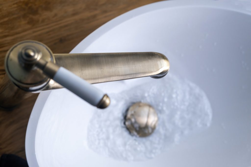 Sink basin faucet, bathroom interior detail. Open bronze tap close up overhead view